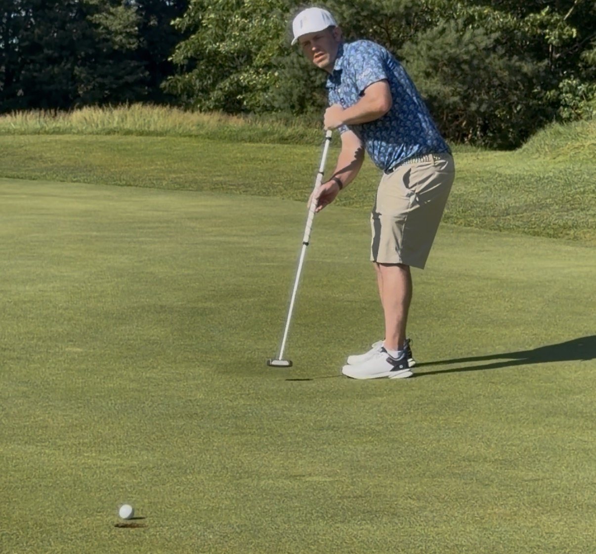 Jeff on a real green in competition, putter in hand, watching his ball drop into the hole.